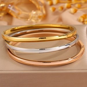 Three-piece set of curved stainless steel bangles in gold, silver, and rose gold finishes