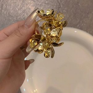 Detailed close-up of a three-dimensional golden metal flower earring with a glossy finish