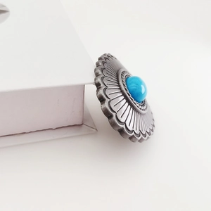 Detailed macro view of vintage zinc alloy belt buckle with sunflower petals and turquoise stone