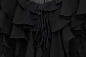 Detail von geschichteten schwarzen Rüschen und zarten Kordelzügen an einer Chiffonbluse