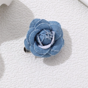 Detailed macro view of denim blue camellia flower brooch with metal clip on back