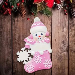 Macro detail of snowman resin ornament in pink Christmas stocking on rustic wood background