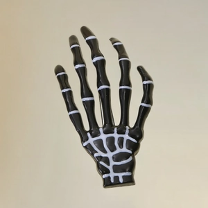 Gothic black skeleton hand hair clip with white bone details on a metallic background
