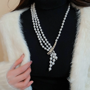 Detail of multi-layer pearl necklace with silver metallic clasp on a black sweater
