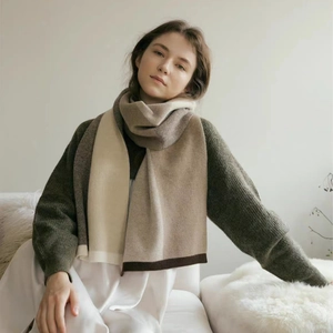 Unisex beige and brown knitted scarf shawl displayed by a model in a cozy setting