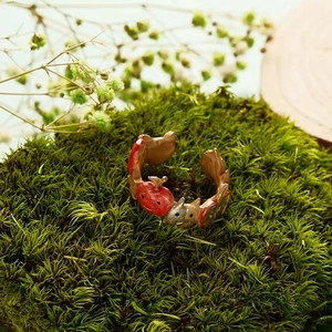 Close-up of adjustable branch ring with red apple and cute rabbit on green moss
