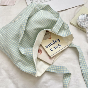 Detailed top view of blue checkered canvas tote bag with woven label and internal lining