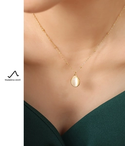 Detailed view of an oval cat-eye stone pendant on a stainless steel bead chain necklace