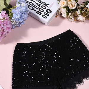 Détail de short noir à paillettes avec bordure en dentelle sur fond rose fleuri