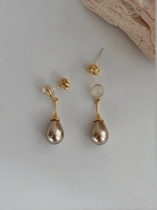 Detail view of drop-shaped champagne pearl earrings with gold-toned textured settings