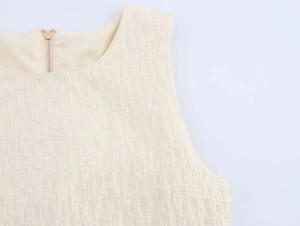 Détail de la texture jacquard crème et fermeture éclair métallique au dos du haut sans manches