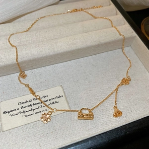 Detail of 18k gold plated necklace with flower, handbag charms and tassel on velvet