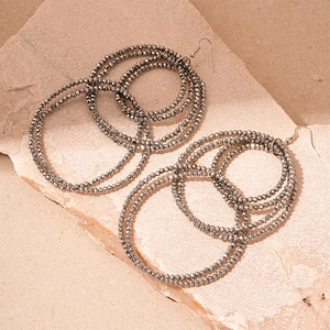 Macro detail of layered silver-gray faceted bead hoop earrings on a textured stone