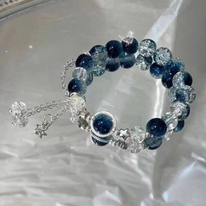 Close-up of blue and crystal beads bracelet with silver star charms on silk background