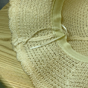 Detail of light yellow woven sun hat interior with adjustable string and gold trim