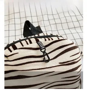 Close-up of zebra stripe plush backpack with cartoon hook and black webbing handle