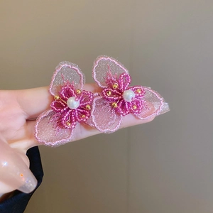 Dettaglio di orecchini floreali in pizzo e perline con perle bianche e tulle rosa cipria