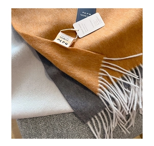 Close-up of three 100% cashmere scarves with fringe details and material care labels