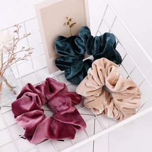 Close-up of velvet checkered hair scrunchies in burgundy, green, and beige in a wire basket