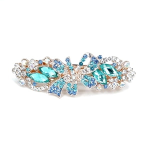 Golden flower spring hair clip with blue and green crystals on a white background