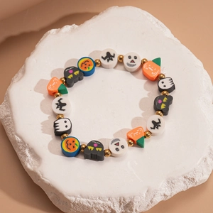 Close-up of Halloween polymer clay bracelet with orange pumpkin and ghost beads on stone