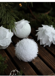 Close-up of white petal foam Christmas balls with glitter on festive pine branch background