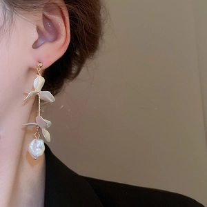 Detailed view of long petal tassel earrings with artificial pearls on model
