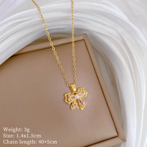 Detail of pink crystal bow pendant with central pearl on gold chain displayed in jewelry box