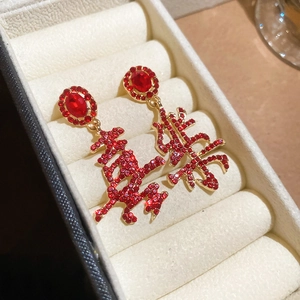 Macro shot of red gemstone and gold-plated Chinese characters in white jewelry box