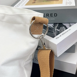 Detail of silver metal ring hook and thick white canvas fabric with khaki woven strap