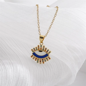 Gold Evil Eye necklace with colorful crystals on white textured fabric background
