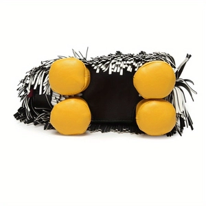 Detail of creative dog-shaped handbag featuring black and white leather tassels and yellow feet