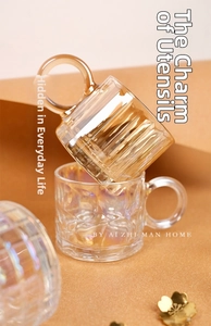 Close-up of luxury amber striped glass mugs with large circular handles for coffee