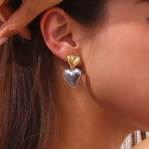 Macro view of double heart stud earrings in 18K gold and silver finish on ear