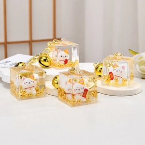 Macro shot of Maneki Neko keychain in oil-filled acrylic cube with golden bells