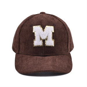 Detail der Cord-Baseballkappe mit M-Chenille-Patch und goldenem Glitzerrand