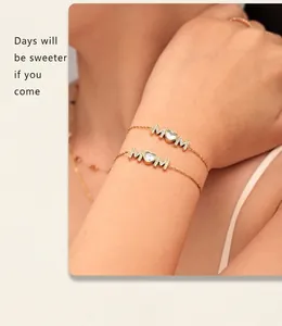 Close-up of golden MOM letter bracelet with heart-shaped zircon on a woman's wrist