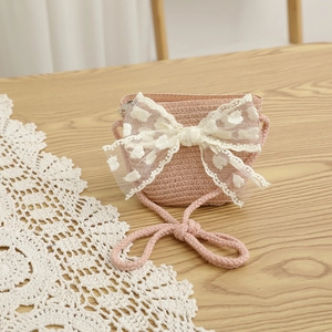 Vue détaillée du sac bandoulière rose tressé avec grand nœud en dentelle blanche