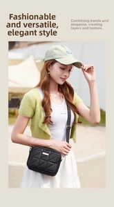 Outdoor model shot of a black quilted crossbody bag with gold plaque and fabric strap