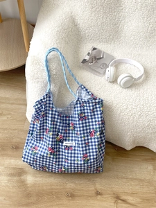 Detail of floral canvas tote bag with blue plaid patterns and rope handle on a chair