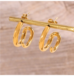 Close-up of gold-plated titanium steel earrings with a double-layered wavy S-shape design
