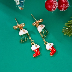 Detail of Christmas stocking bow earrings with red and green enamel on festive background