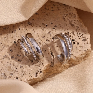 Detail of silver triple C-shaped stud earrings with zircons on a natural stone background