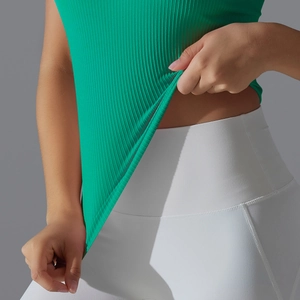Détail du haut de sport côtelé vert vif et du legging blanc à taille haute et coutures fines
