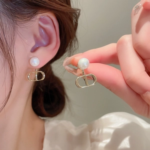 Elegant gold CD letter drop earrings with white pearls for women on model ear