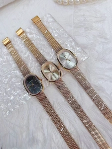 Detailed display of oval quartz watches with golden mesh straps on a plush background
