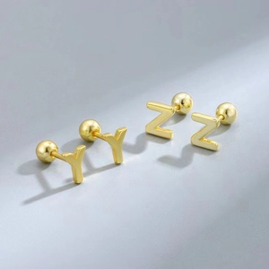 Detail of gold letter Y and Z earrings with secure screw ball backing on gray background