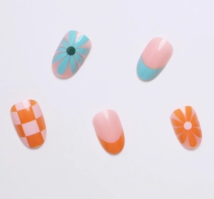 Detail of pink press-on nails with daisy patterns, blue checkerboard and French tips