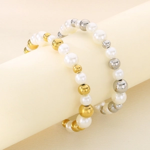 Détail de boucles d'oreilles créoles avec perles d'eau douce et billes métalliques dorées