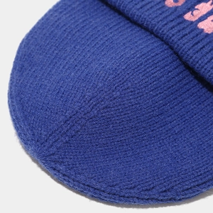 Dettaglio macro del berretto in maglia blu reale con ricamo di lettere rosa